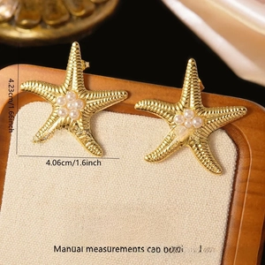 Detail of gold starfish earrings with white pearls and stainless steel texture