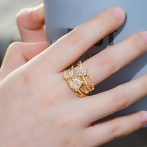 Layered gold ring with AAA baguette-cut zircons on a woman's hand with grey cup background