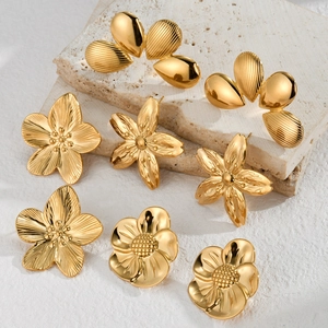 Set of minimalist gold flower stud earrings in vintage French style on a stone plate
