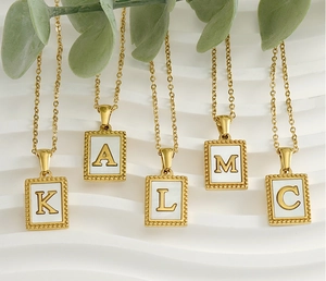 Detailed view of 18K gold-plated square shell letter pendants on fine steel chains