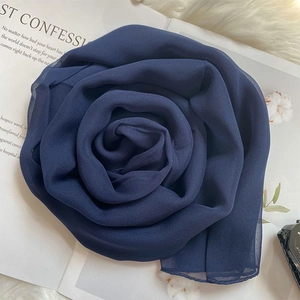 Detail of navy blue chiffon silk scarf creatively folded in a rose shape on soft texture