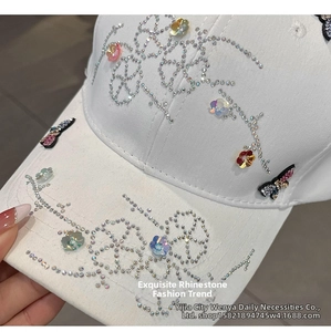 Close-up of white baseball cap with rhinestone butterfly patch and floral decorations