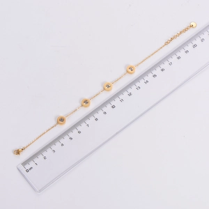 Flat lay of minimalist gold chain bracelet with Roman numeral charms and scale measurement