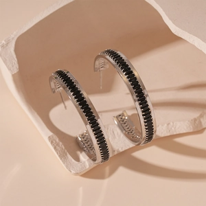 Detail of C-shaped earrings with black zircon stones and silver metal finish
