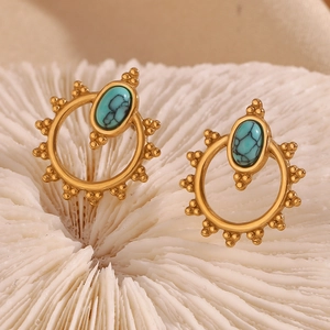 Macro shot of bohemian gold earrings with oval turquoise and beaded floral border