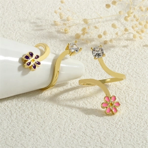 Detail of gold spiral open rings with colorful enamel flowers and sparkling zircon stones