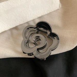 Macro detail of gunmetal camellia hair claw clip with polished metallic finish