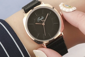 Close-up of stylish ladies watch with rose gold case and black magnetic mesh strap