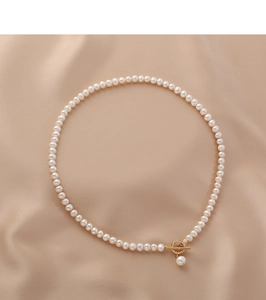 Detailed close-up of natural freshwater pearl necklace with gold OT buckle on silk fabric