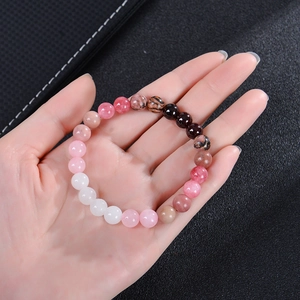 Bracelet en perles de quartz fraise et grenat tenu à la main sur cuir noir élégant