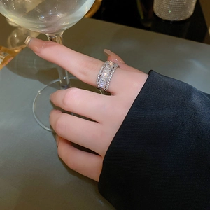 Macro shot of silver zircon ring with rectangle crystals worn on model holding glass