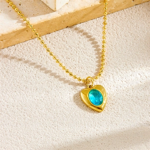 Gold beaded necklace with heart pendant featuring a blue oval gemstone on stone base