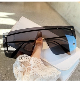Detail showing oversized square frames with metal rivets and gradient dark grey lenses