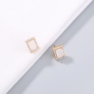 Elegant gold four-leaf clover earrings with rectangle zircon on white knit fabric