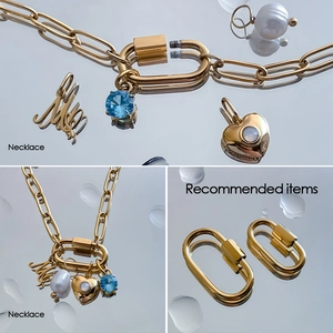 Macro detail of gold-plated carabiner clasp and mixable charms on chunky chain necklace