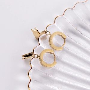 Minimalist gold butterfly hoop earrings displayed on a textured glass tray for women