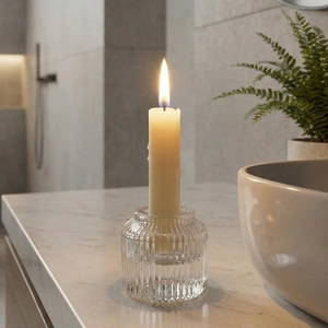 Portacandele elegante in vetro a coste con candela crema accesa su piano in marmo