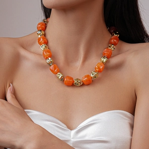 Close-up of Bohemian orange and gold beaded shell necklace on a female model