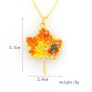 Detail of maple leaf pendant with colorful enamel gradients and sparkling gemstones