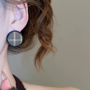 Close-up of retro plaid fabric round stud earrings with black frame worn by model