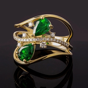 Vista macro de anillo de oro 18K con esmeraldas talla pera y detalles de diamantes