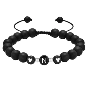 Détail de perles noires mates 8mm avec lettre N et breloque cœur sur bracelet tissé