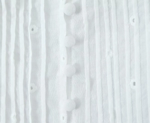 Dettaglio di top in cotone bianco con bottoni rivestiti in tessuto e trama a pieghe