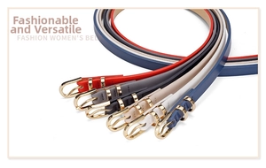 Detail view of five skinny leather belts in assorted colors with golden horseshoe buckles