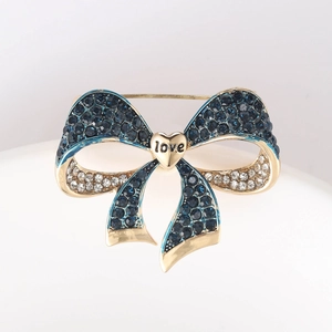 Detailed macro of gold bow brooch with blue crystals and a heart love pendant