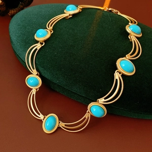 Detail of vintage gold necklace with turquoise oval stones on a green velvet stand