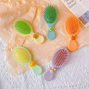 Set of five colorful cartoon air cushion hair combs on aesthetic soft fabric background