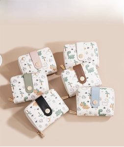 Flat lay of multiple colorful Baellerry mini wallets with cute dinosaur prints and snap buttons