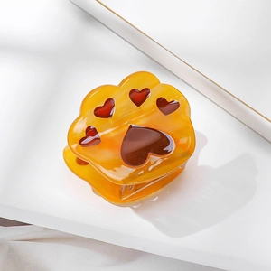 Amber acetate cat paw hair claw clip with brown heart-shaped pads on white surface