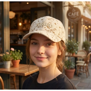 Detail of embroidered NY letters on a cream speckled baseball cap worn outdoors