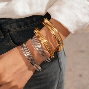 Close-up of geometric layered twisted metal bangles in gold and silver finish on a wrist