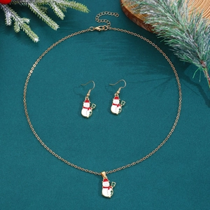 Detail eines Weihnachts-Schmucksets mit Schneemann-Halskette und Ohrringen auf einem Tannenzweig
