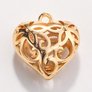 Macro view of gold heart pendant with intricate floral filigree cutout and hanging loop