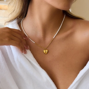 Golden heart pendant pearl necklace featuring a mixed chain design on female model