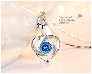 Macro shot of silver heart pendant with deep blue crystal and sparkling side diamonds