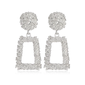 Macro de boucles d'oreilles en métal argenté avec formes géométriques et textures