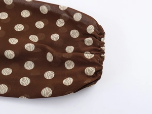 Detailed macro view of elastic cuffs on a brown polka dot chiffon pleated dress