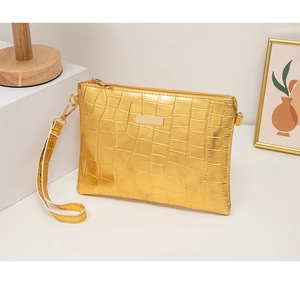 Detail of golden crocodile embossed texture on luxury handbag with metal plaque