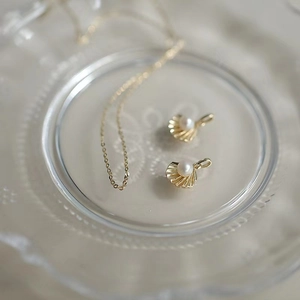 Macro shot of 14k gold plated shell pendant with pearl on a textured glass plate