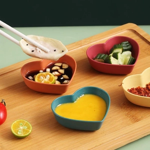 Heart-shaped wheat straw seasoning dishes in four colors on a wooden serving tray