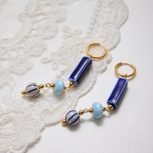 Detail of vintage blue ceramic beaded earrings with gold hoops on white lace background