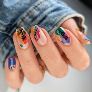 Abstract press-on nails with colorful geometric shapes and black leaf patterns on milk white base