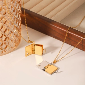 Minimalist stainless steel book pendant necklaces in gold and silver on a jewelry display
