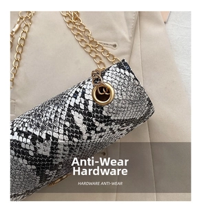 Detail of snake pattern texture and gold anti-wear hardware on cylinder bag