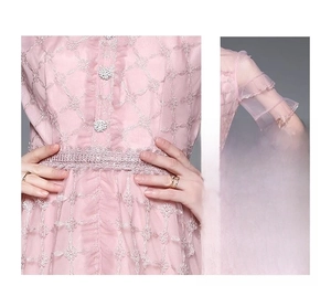 Détail de la robe en dentelle rose avec broderie en fil d'or et taille élastique