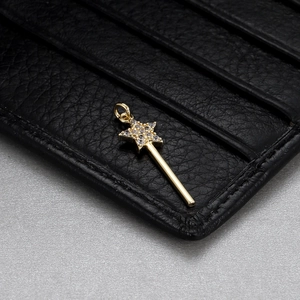 Close-up of a gold star magic wand pendant with clear crystals on a black leather texture